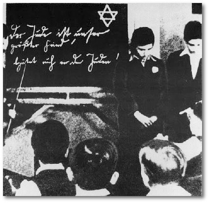 Um 1935: Zwei jdische Schler werden vor ihren Klassenkameraden gedemtigt. An der Tafel antisemitische Hetze: 'Der Jude ist unser grter Feind! Schtzt Euch vor den Juden!' 