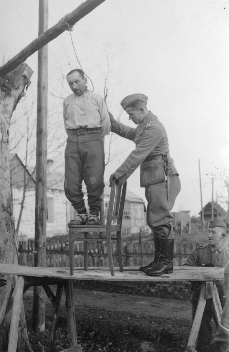 Ein Angehöriger der deutschen Polizei hängt einen Mann in der besetzten UdSSR. 